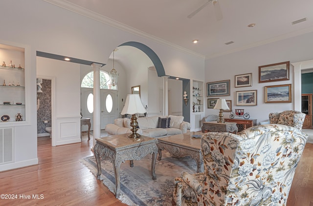 living room with crown molding, light hardwood / wood-style flooring, ceiling fan, built in features, and decorative columns