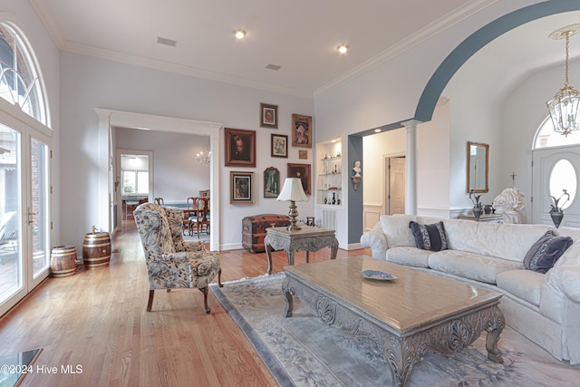 living room with decorative columns, crown molding, and light hardwood / wood-style floors