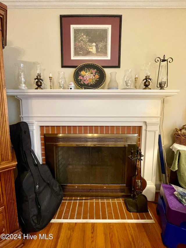 details with hardwood / wood-style flooring, a brick fireplace, and ornamental molding