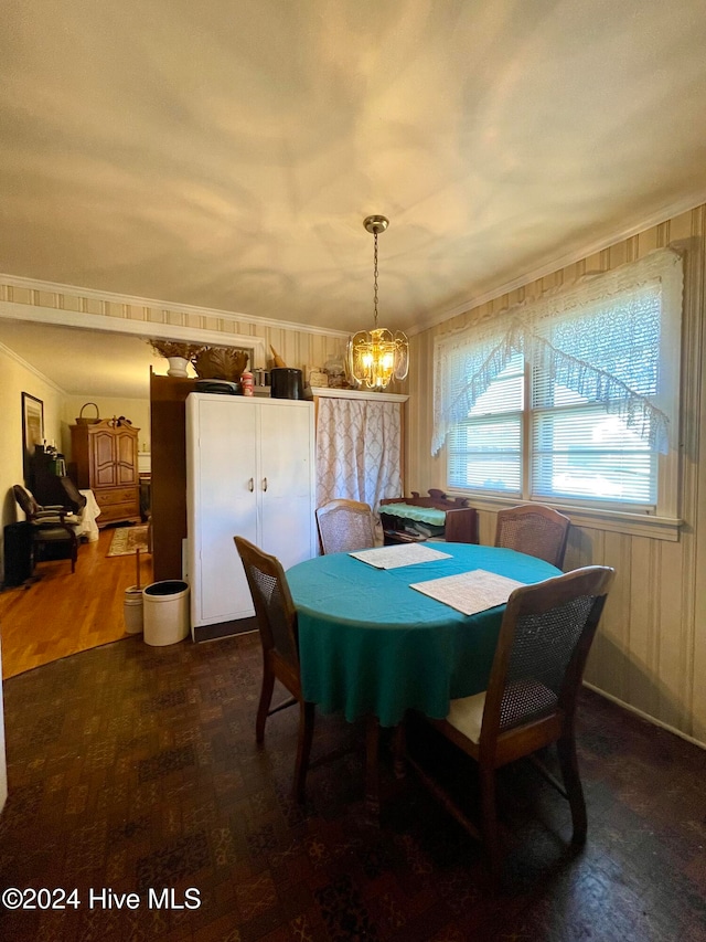 dining room featuring a notable chandelier, dark hardwood / wood-style flooring, crown molding, and wooden walls