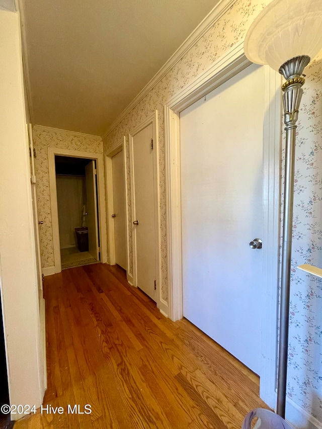 hallway with wood-type flooring and ornamental molding