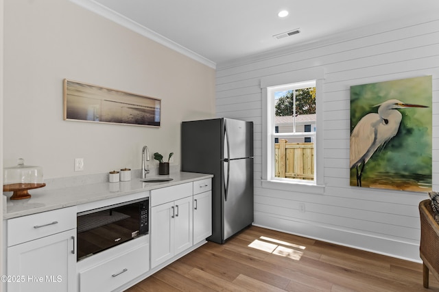 1514 Mackerel Ln, Carolina Beach, NC 28428 - kitchen with visible vents, a sink, freestanding refrigerator, black microwave, and crown molding