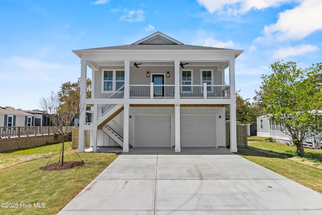 1514 Mackerel Ln, Carolina Beach, NC 28428 - beach home with concrete driveway, a front lawn, a ceiling fan, and stairs