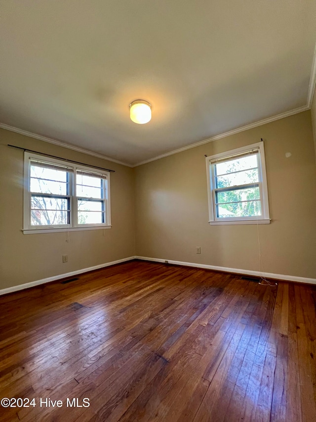 unfurnished room featuring ornamental molding and dark wood-type flooring