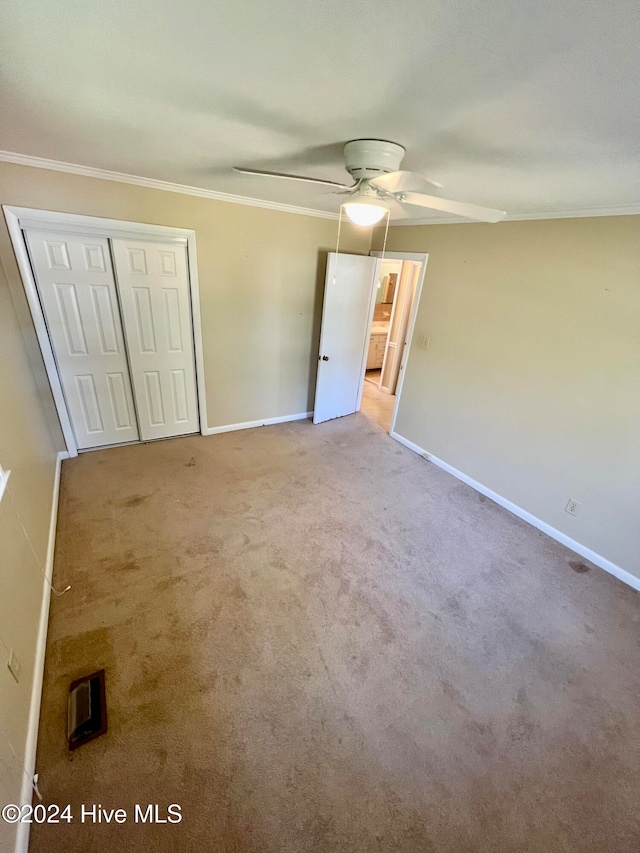 unfurnished bedroom featuring ceiling fan, crown molding, light carpet, and a closet