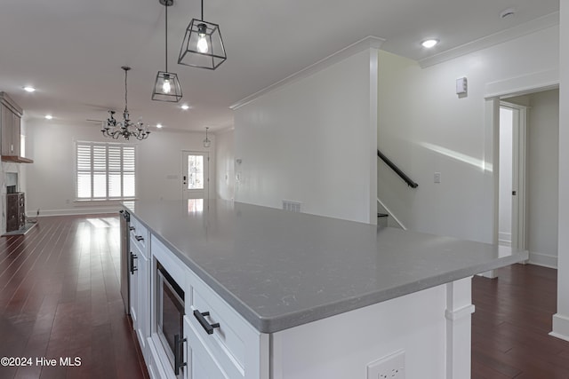 kitchen with white cabinets, dark hardwood / wood-style floors, hanging light fixtures, and dark stone countertops