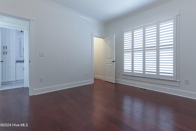 spare room with crown molding and dark wood-type flooring