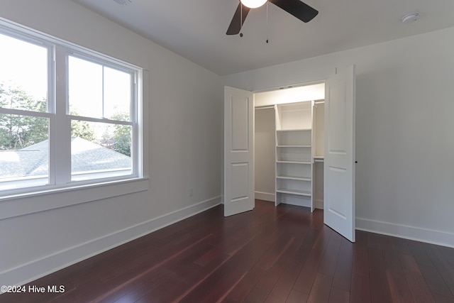 unfurnished bedroom featuring dark hardwood / wood-style floors, ceiling fan, a walk in closet, and a closet