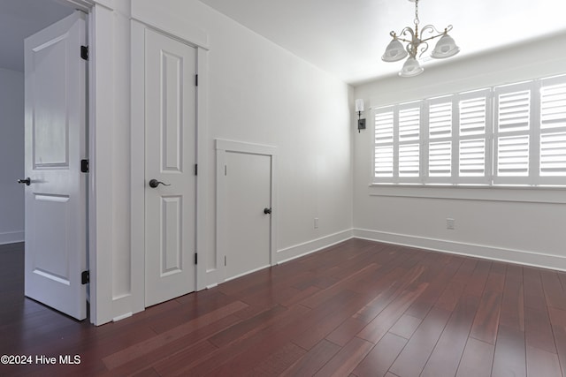 unfurnished room with a chandelier and dark hardwood / wood-style floors