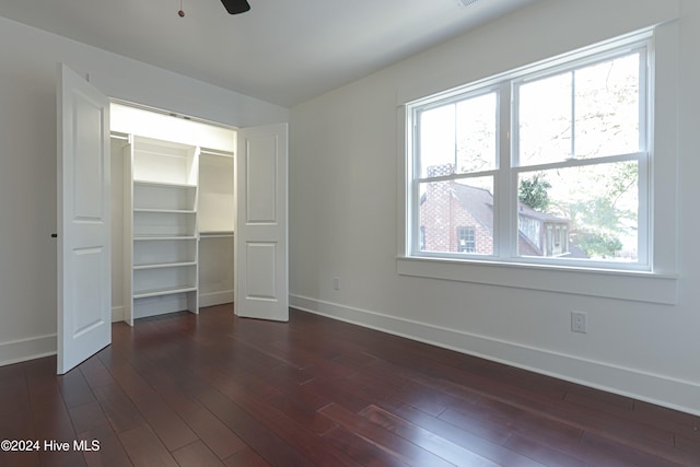 unfurnished bedroom featuring a closet, dark hardwood / wood-style floors, multiple windows, and ceiling fan