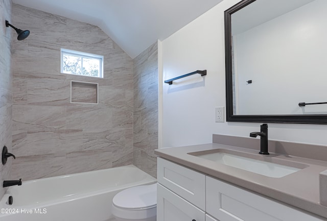 full bathroom featuring toilet, vanity, lofted ceiling, and tiled shower / bath