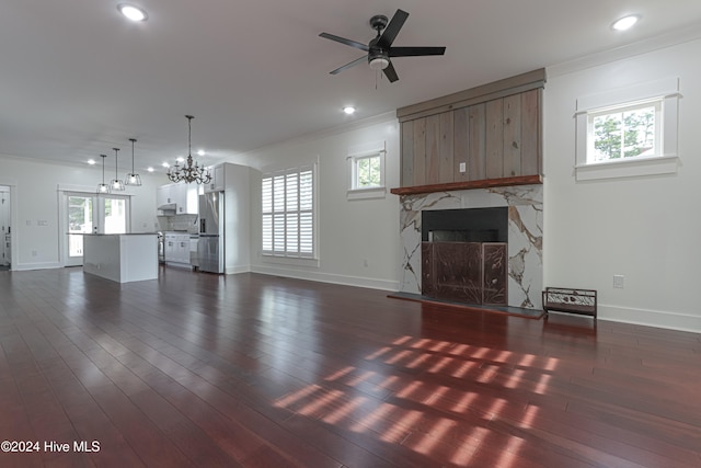 unfurnished living room featuring crown molding, a wealth of natural light, dark wood-type flooring, and a premium fireplace