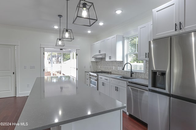 kitchen featuring sink, a center island, stainless steel appliances, pendant lighting, and white cabinets