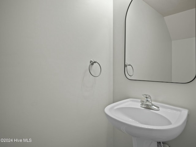 bathroom featuring lofted ceiling and sink