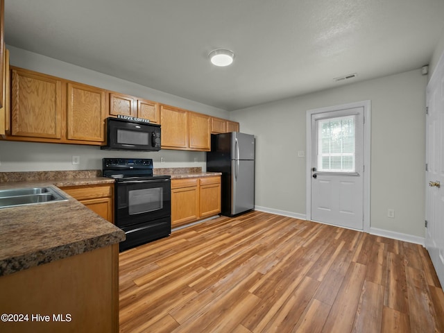 kitchen featuring black appliances, sink, and light hardwood / wood-style flooring