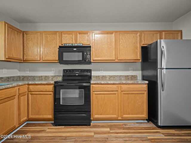 kitchen with light wood-type flooring and black appliances