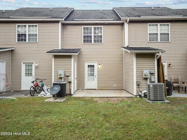 rear view of house featuring a patio, central AC, and a lawn