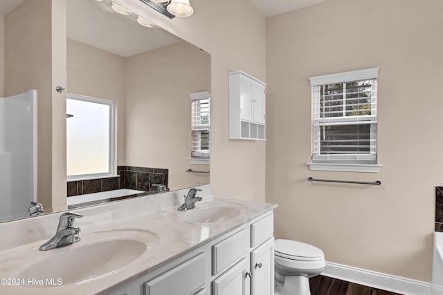 bathroom with hardwood / wood-style flooring, vanity, toilet, and a tub to relax in