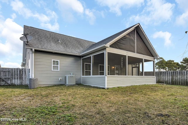 back of house featuring a sunroom, a lawn, and central AC