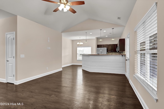 unfurnished living room with ceiling fan with notable chandelier, dark hardwood / wood-style floors, and vaulted ceiling