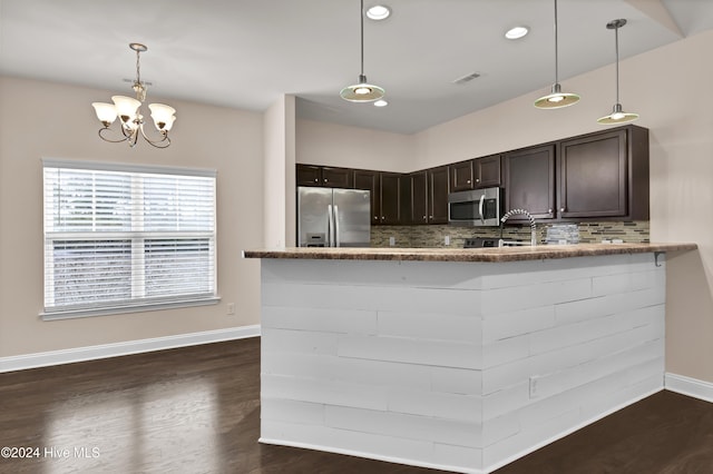 kitchen with decorative light fixtures, kitchen peninsula, stainless steel appliances, and tasteful backsplash