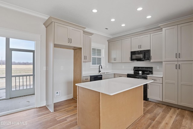 kitchen with a wealth of natural light, a center island, a sink, and black appliances