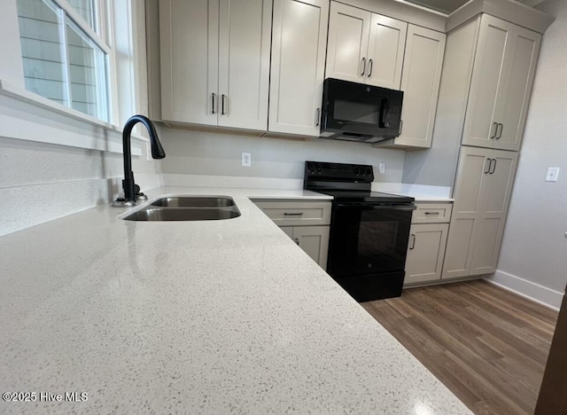 kitchen featuring baseboards, dark wood-style floors, light countertops, black appliances, and a sink