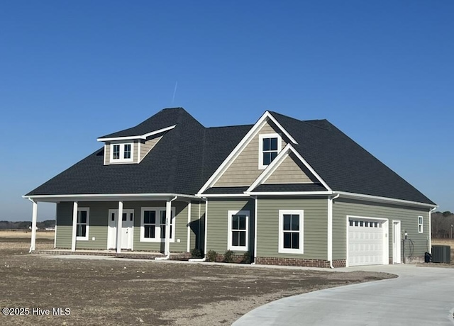 view of front of property with covered porch, central AC, driveway, and a garage