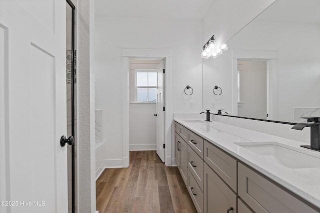 bathroom featuring double vanity, a sink, baseboards, and wood finished floors