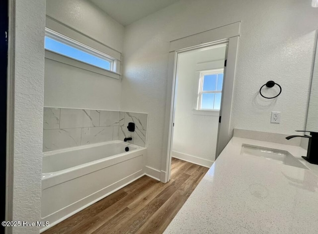 full bathroom with a garden tub, baseboards, wood finished floors, and a healthy amount of sunlight