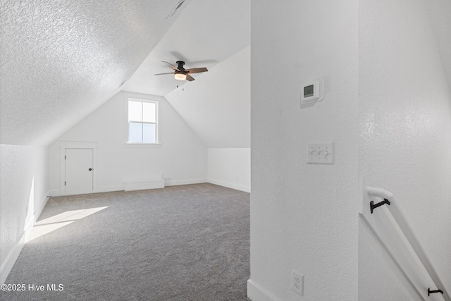 additional living space featuring a textured ceiling, a ceiling fan, baseboards, vaulted ceiling, and carpet