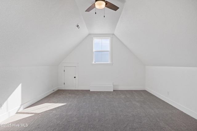 bonus room featuring baseboards, visible vents, lofted ceiling, a textured ceiling, and carpet flooring