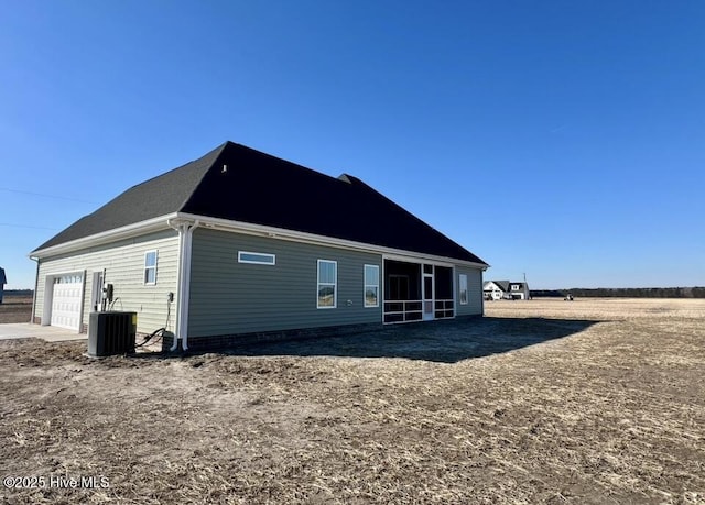 back of house with a garage and central AC unit