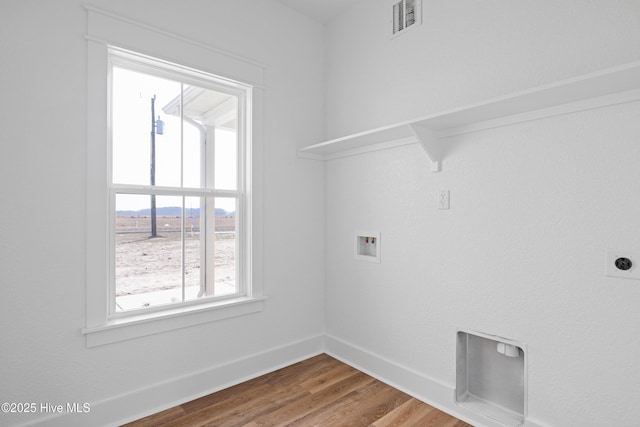 laundry area with laundry area, washer hookup, wood finished floors, visible vents, and baseboards