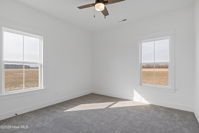 carpeted empty room with a ceiling fan, visible vents, and baseboards