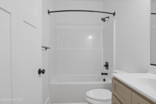 bathroom featuring toilet, a textured wall, vanity, and bathing tub / shower combination