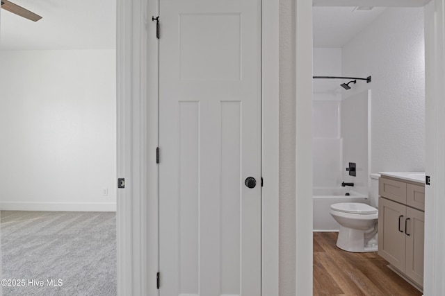 full bathroom with toilet, a ceiling fan, vanity, wood finished floors, and  shower combination