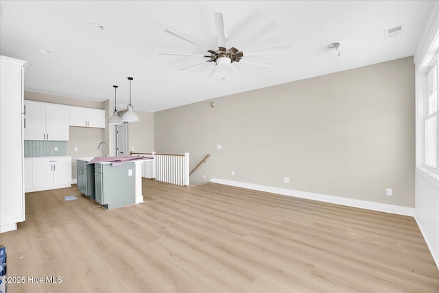 820 Kenneth Ave Unit 1, Carolina Beach, NC 28428 - kitchen featuring ceiling fan, decorative backsplash, an island with sink, and light wood-style floors