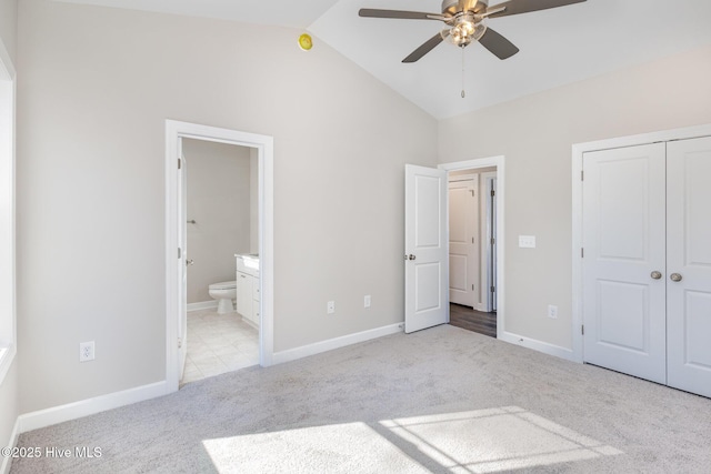 unfurnished bedroom featuring light carpet, connected bathroom, high vaulted ceiling, and ceiling fan