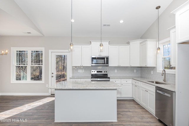 kitchen with sink, white cabinetry, light stone counters, decorative light fixtures, and stainless steel appliances