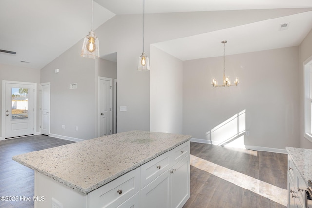 kitchen featuring light stone counters, a center island, hanging light fixtures, dark hardwood / wood-style flooring, and white cabinets