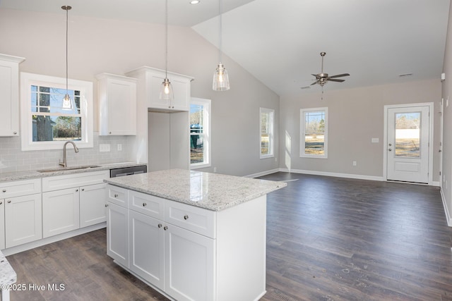 kitchen with decorative light fixtures, a center island, sink, and white cabinets