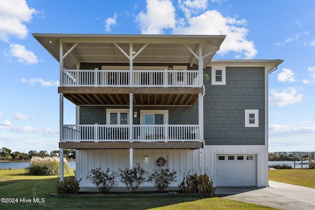 view of front of property featuring a balcony, a water view, a front yard, and a garage