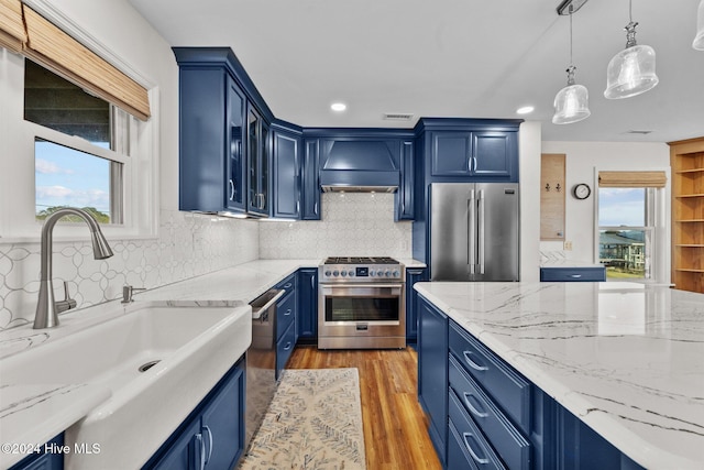 kitchen with blue cabinets, high end appliances, and custom exhaust hood