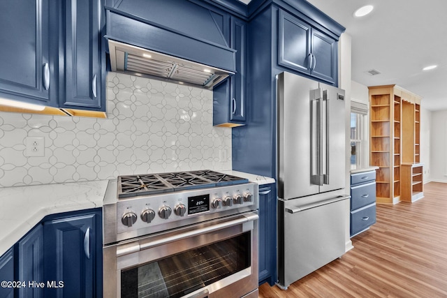 kitchen with high end appliances, custom range hood, blue cabinets, and tasteful backsplash