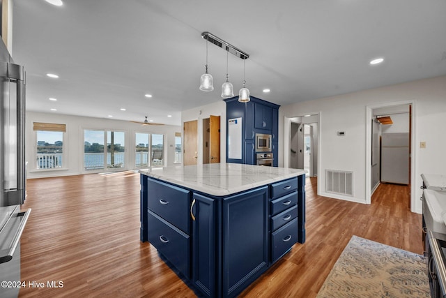 kitchen with blue cabinetry, ceiling fan, stainless steel appliances, light hardwood / wood-style flooring, and a kitchen island