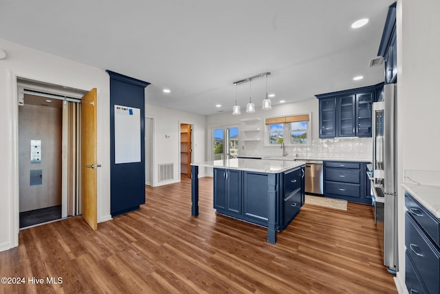 kitchen featuring hardwood / wood-style floors, blue cabinets, a kitchen island, a kitchen bar, and stainless steel appliances