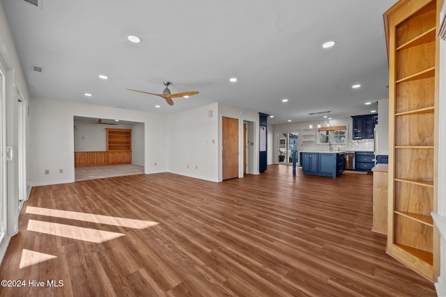 unfurnished living room featuring ceiling fan, sink, and dark hardwood / wood-style floors