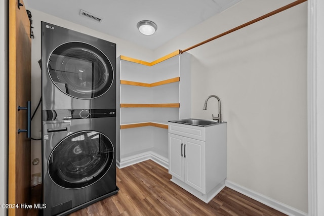 clothes washing area featuring dark hardwood / wood-style flooring, stacked washer and clothes dryer, and sink