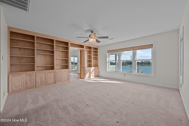 unfurnished living room featuring a water view, ceiling fan, and light colored carpet